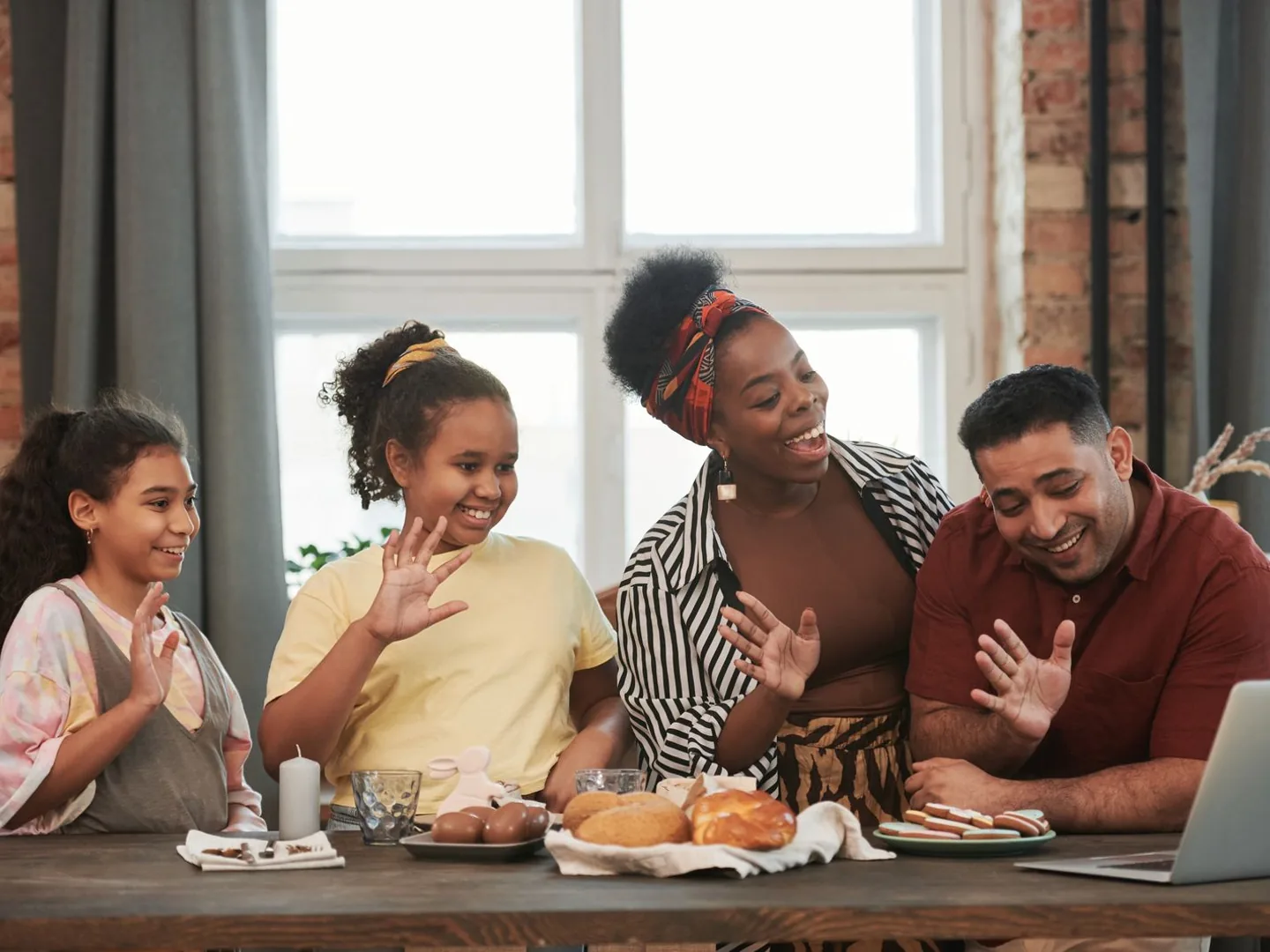 Cena ilustrativa de uma família sorrindo e acenando durante uma videochamada.