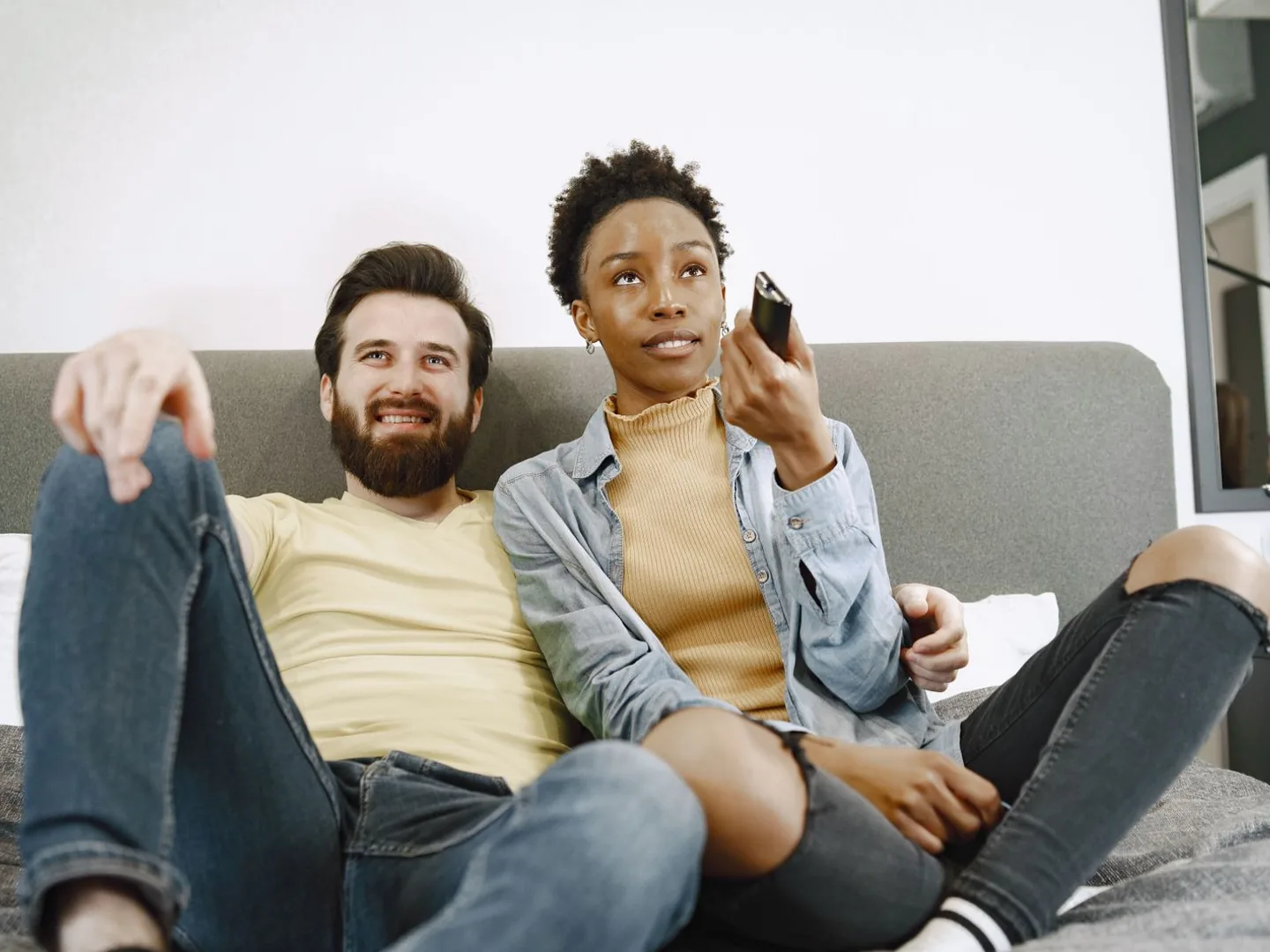 Cena ilustrativa de um casal sentado no sofá assistindo à televisão.